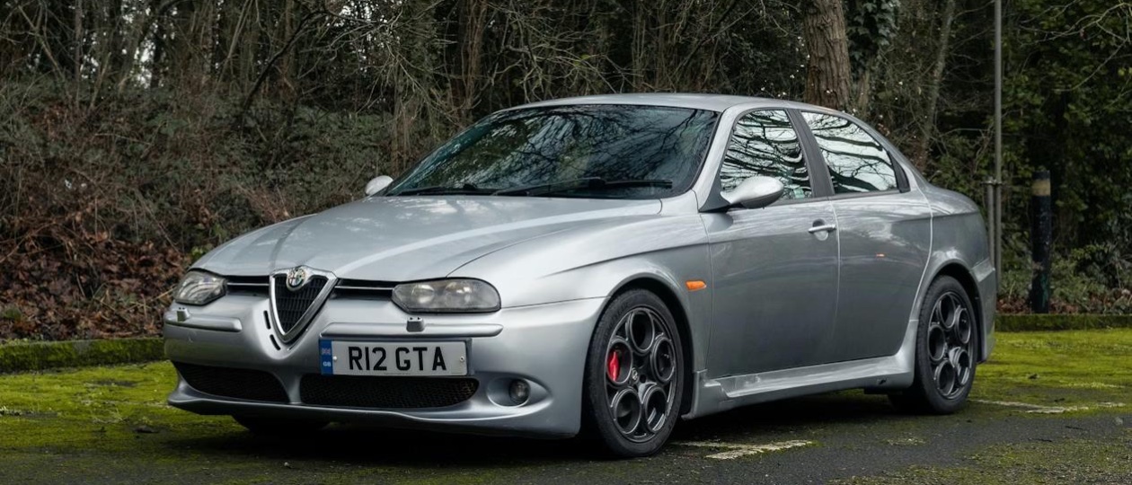 A silver Alfa Romeo 156 GTA sedan on a winding Italian mountain road