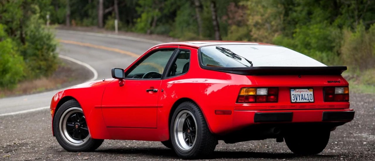 A guards red Porsche 944 Turbo parked on a winding alpine road at golden hour
